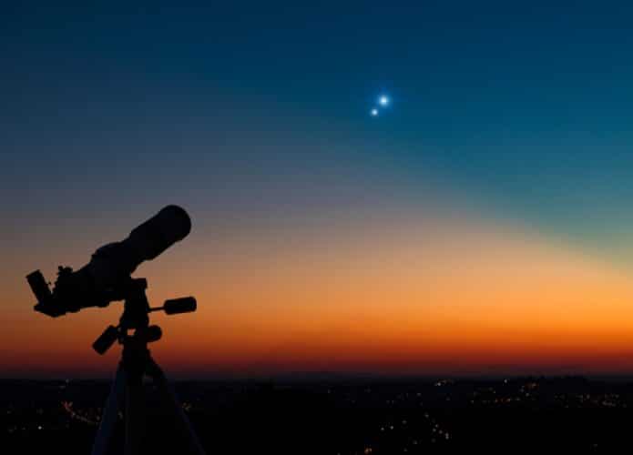 Telescópio em direção ao horizonte laranja e azul e dois ponto brilhantes alinhados