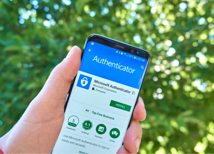 Pessoa segura smartphone exibindo página de download do Microsoft Authenticator na Play Store