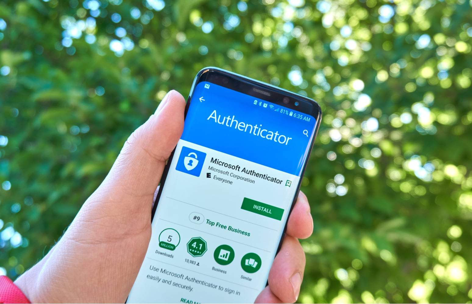 Pessoa segura smartphone exibindo página de download do Microsoft Authenticator na Play Store