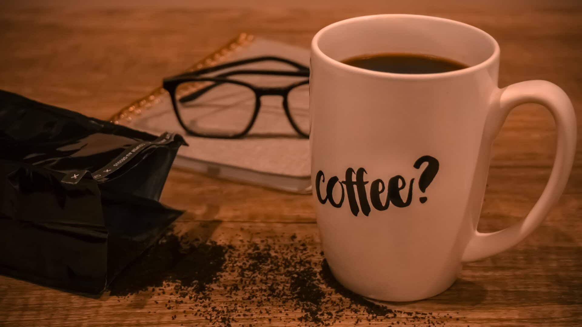 Xícara de café, óculos e papeis sobre uma mesa