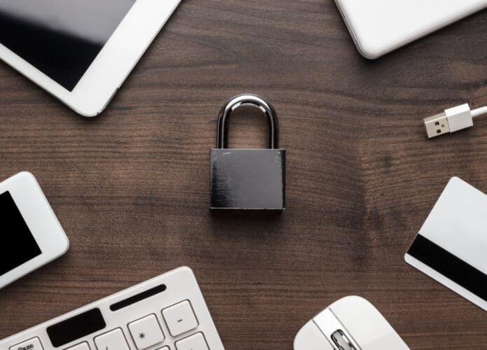 Cadeado em meio a celular, tablet, teclado, mouse e outros acessórios