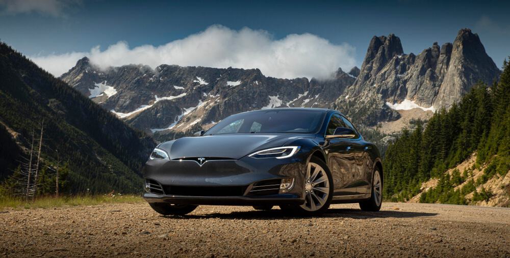 tesla model 3 estacionando diante de montanhas e lago
