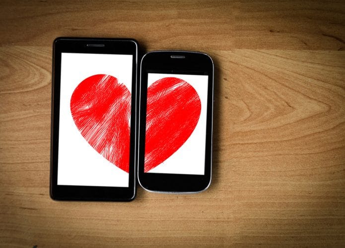 Coração formado por duas metades, cada uma exibida em uma tela de smartphone