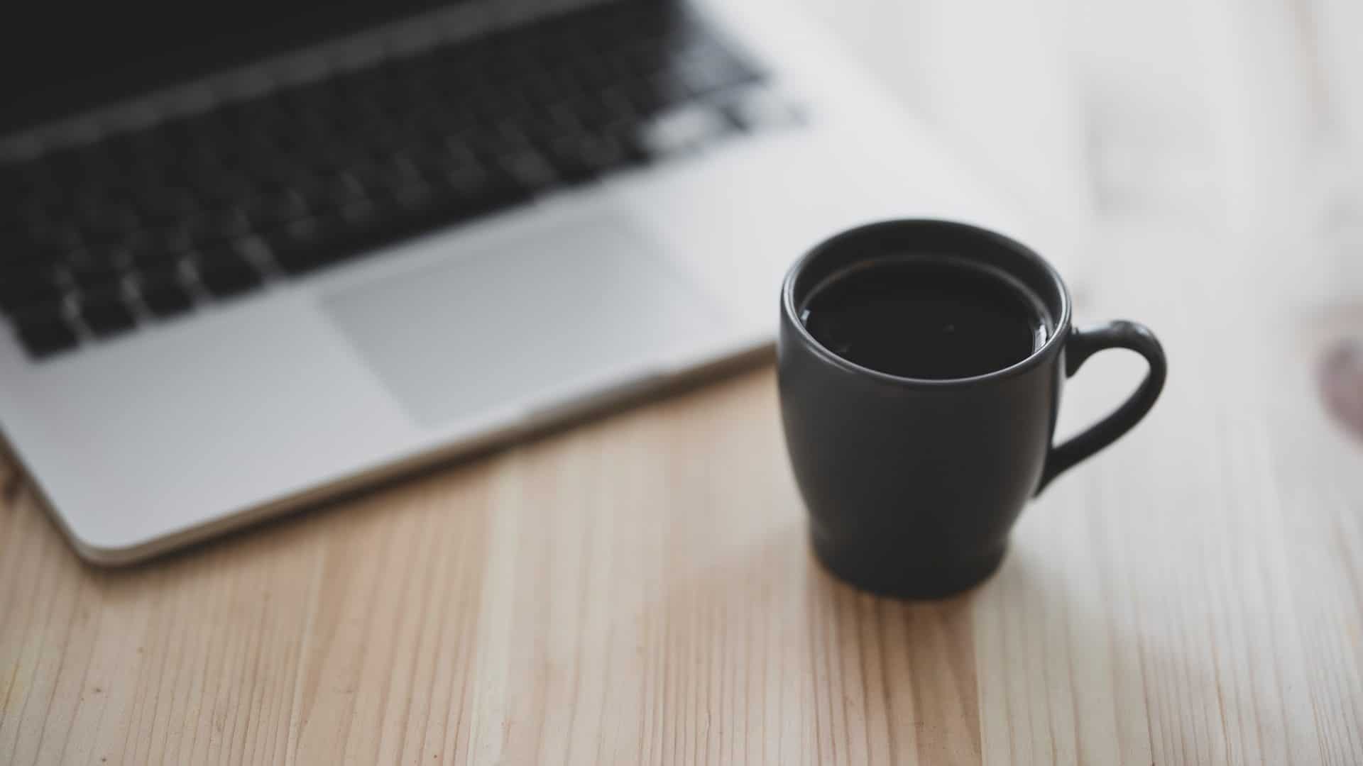 notebook e uma xícara de café sobre a mesa