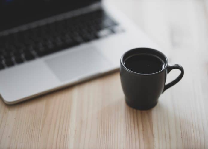 notebook e uma xícara de café sobre a mesa