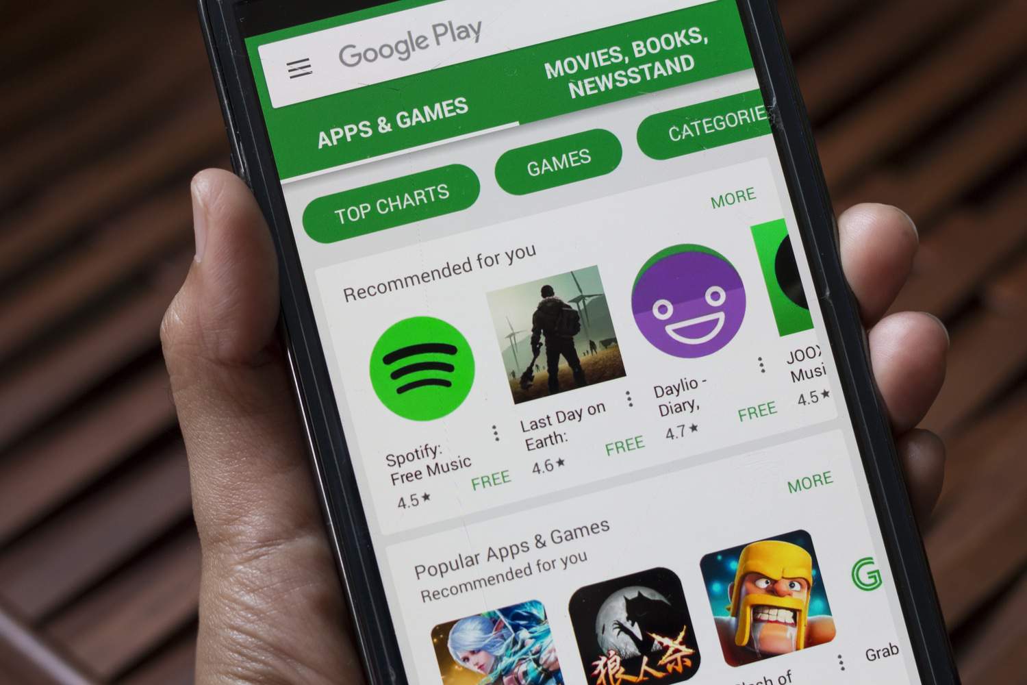 Mão segura smartphone exibindo a tela principal da Google Play