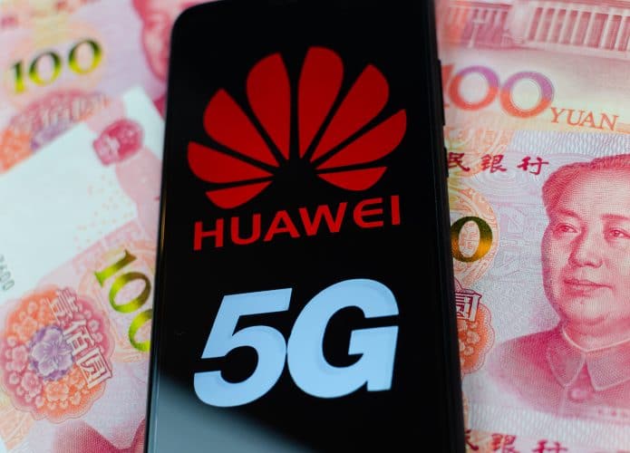 Tela de smartphone exibe logo da empresa Huawei e a palavra 5G em cima de cédulas chinesas