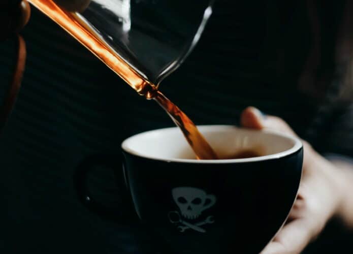 café despejando em xícara preta