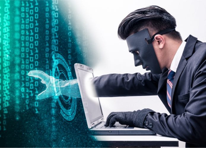 Imagem conceitual mostra um hacker mascarado esticando a mão dentro de um computador, para roubar uma base de dados sigilosos