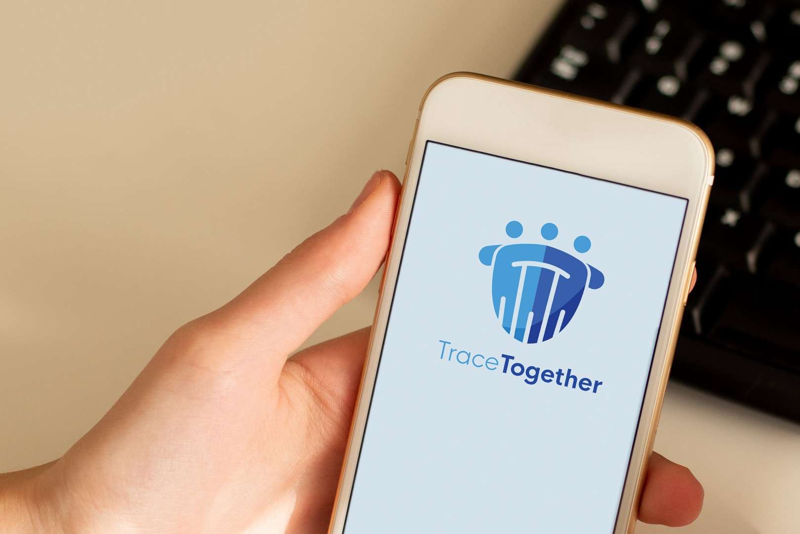 Mão segurando um smartphone branco com o aplicativo Trace Together