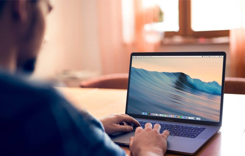 Imagem mostrando um computador Macbook Pro, em uso por um homem
