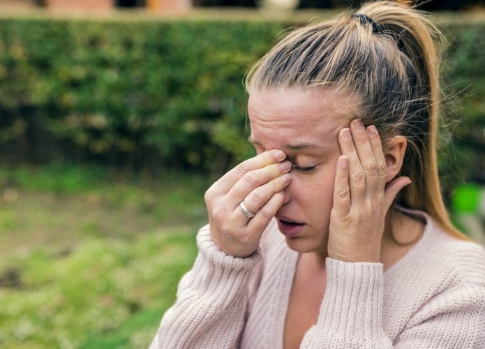 Mulher apertando o nariz e a testa devido a dores de cabeça