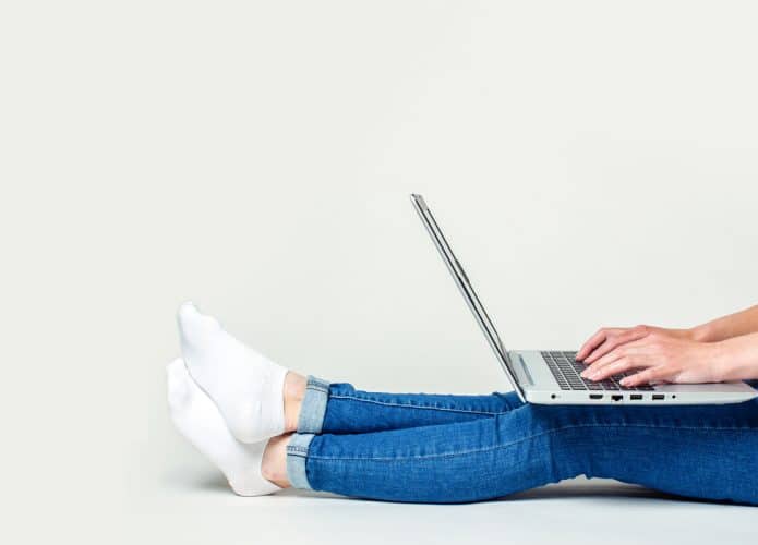 jovem sentado no chão com notebook no colo