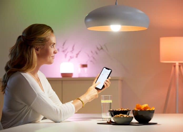 Imagem mostra mulher controlando uma lâmpada inteligente WiZ usando um smartphone