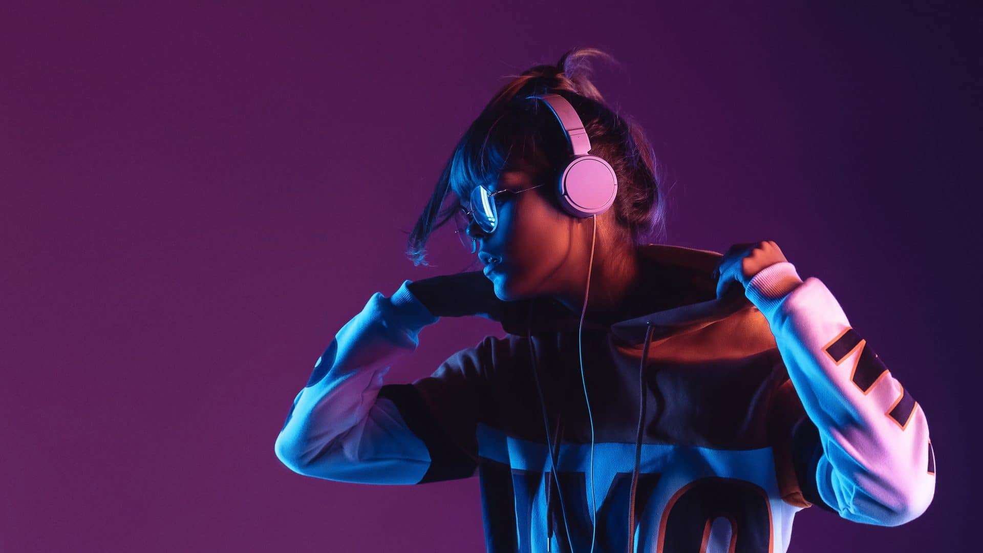 Menina ouvindo música com fone de ouvido em imagem com fundo roxo