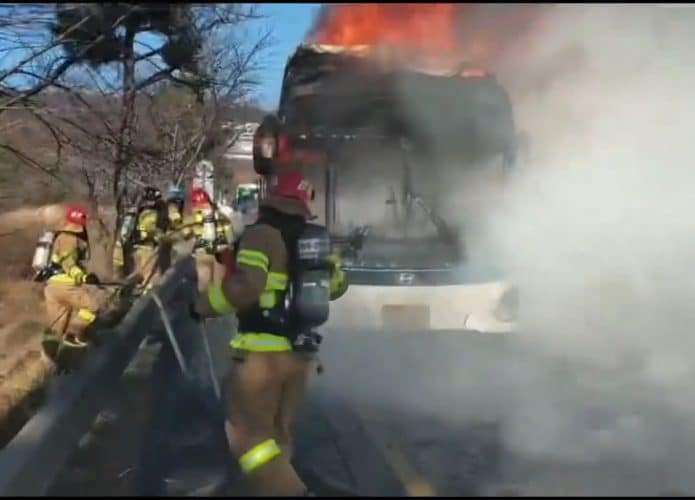 Imagem do ônibus elétrico da Hyundai incendiado, enquanto bombeiros tentam controlar as chamas