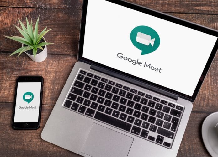 Imagem mostra um notebook e um celular em cima de uma mesa de madeira, ambos estão com o ícone do aplicativo do Google Meet na tela