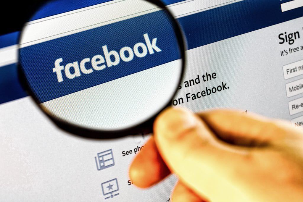 uma lupa expandindo a logomarca do facebook