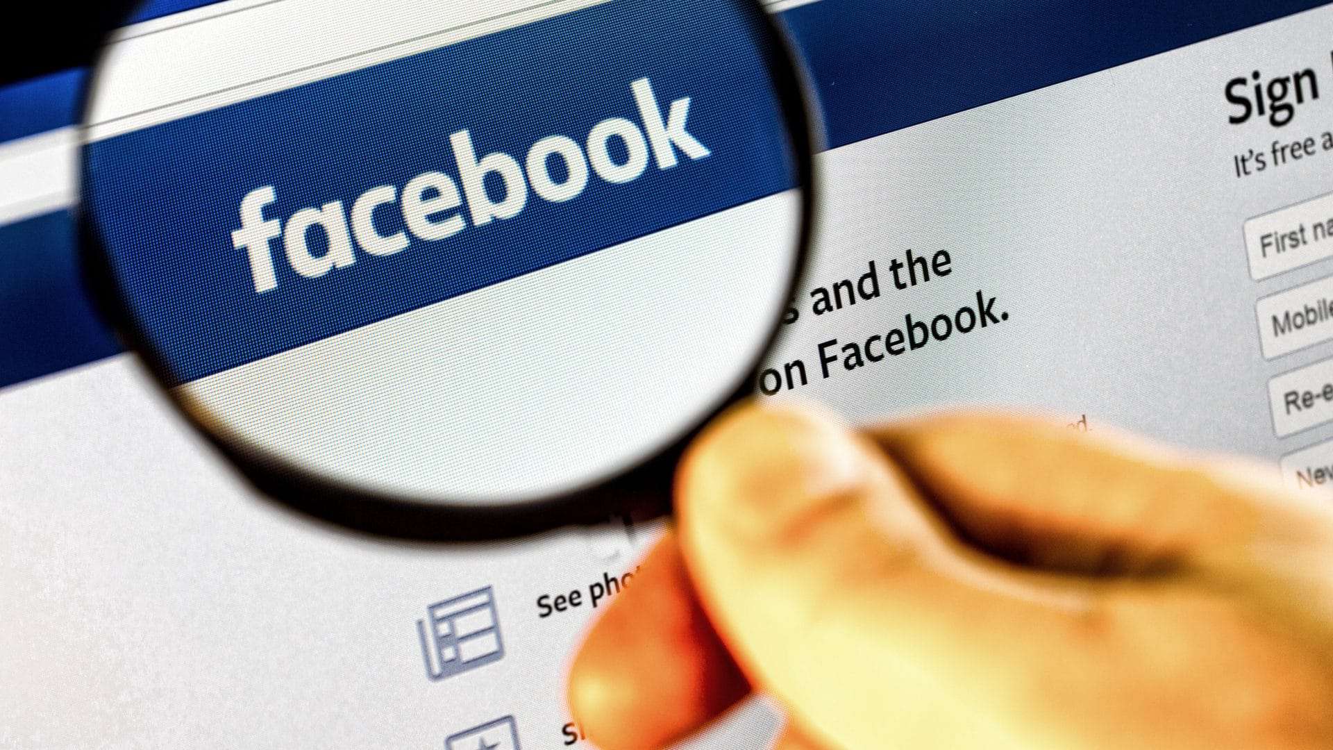 uma lupa expandindo a logomarca do facebook