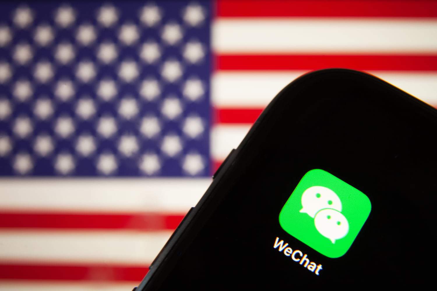 Smartphone exibindo ícone do WeChat na tela com bandeira dos Estados Unidos ao fundo