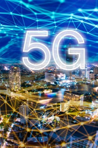 Cidade ilustrada à noite. Por cima há uma rede de luz, como se fosse uma rede de conexão à Iinternet, com o texto 5G por cima.