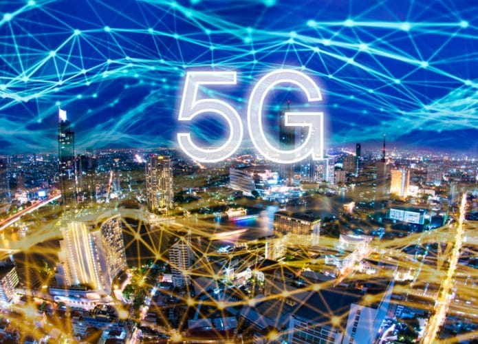 Cidade ilustrada à noite. Por cima há uma rede de luz, como se fosse uma rede de conexão à Iinternet, com o texto 5G por cima.