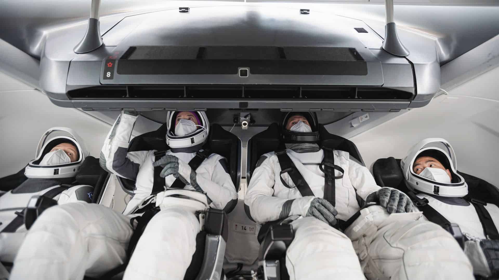Astronautas da Crew-2, usando trajes espaciais, treinam a bordo de uma cápsula Crew Dragon