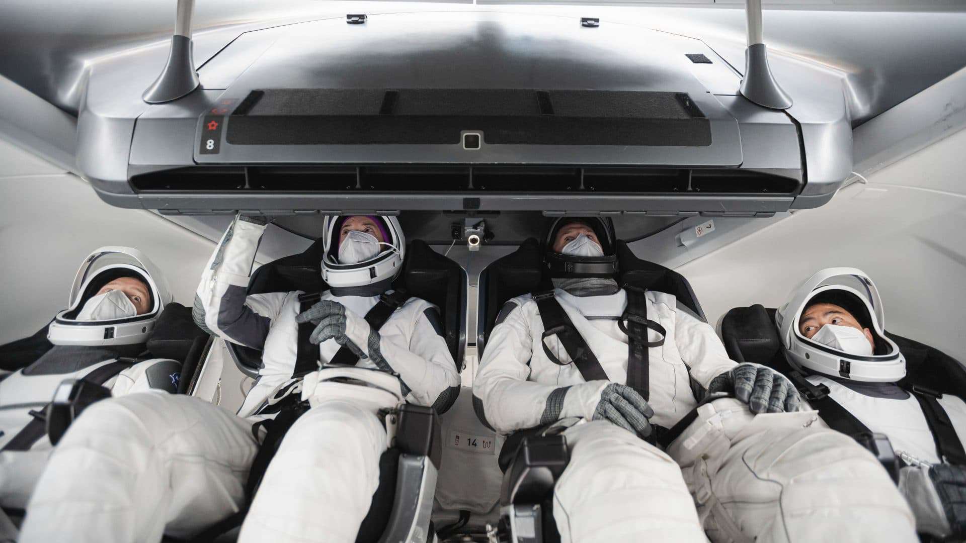 Astronautas da Crew-2, usando trajes espaciais, treinam a bordo de uma cápsula Crew Dragon
