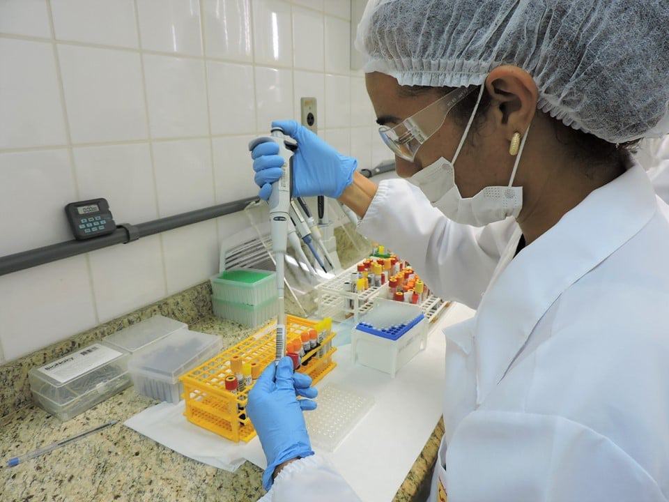 Profissional do Lacen examinando amostras de sangue