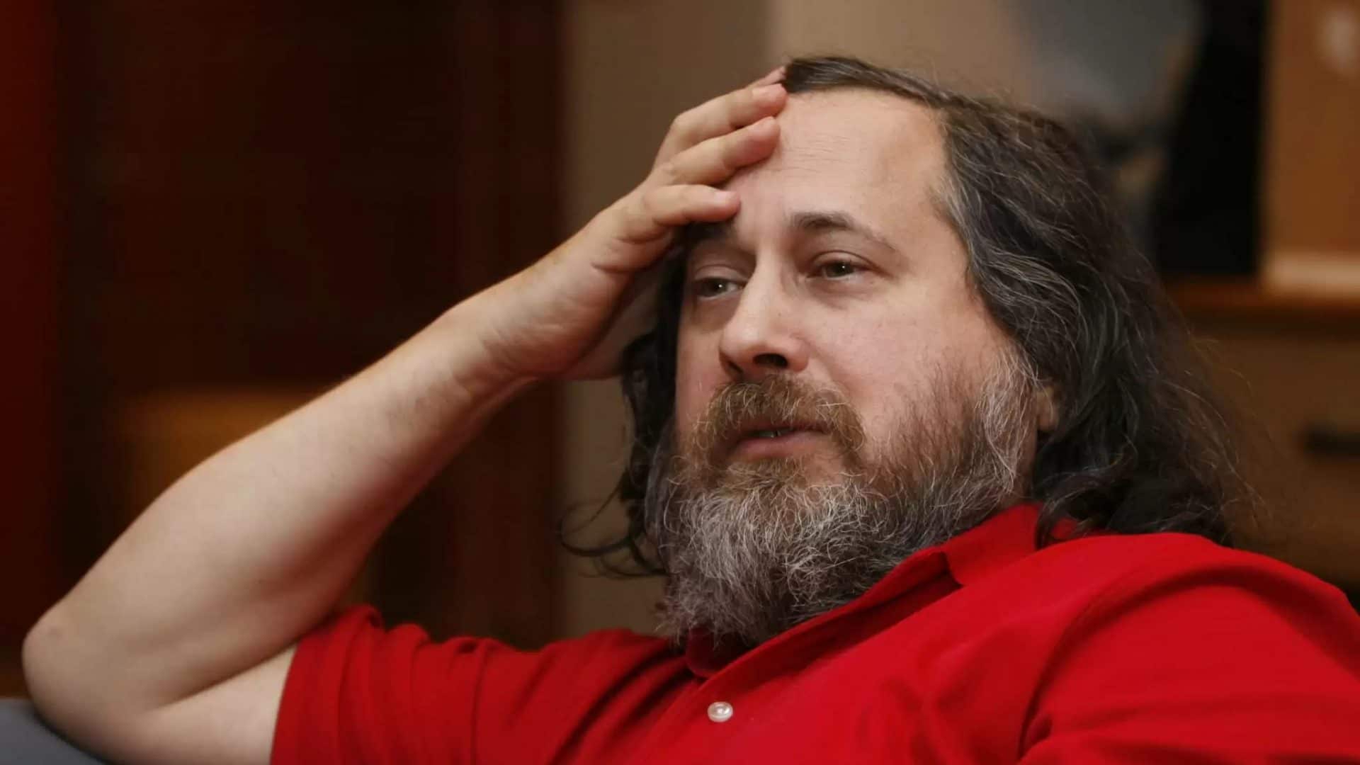 Imagem mostra Richard Stallman, creditado como co-inventor do Linux, com camiseta pólo vermelha, cabelos e barbas longos e a mão na testa