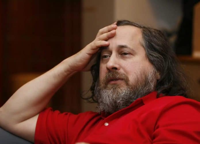 Imagem mostra Richard Stallman, creditado como co-inventor do Linux, com camiseta pólo vermelha, cabelos e barbas longos e a mão na testa