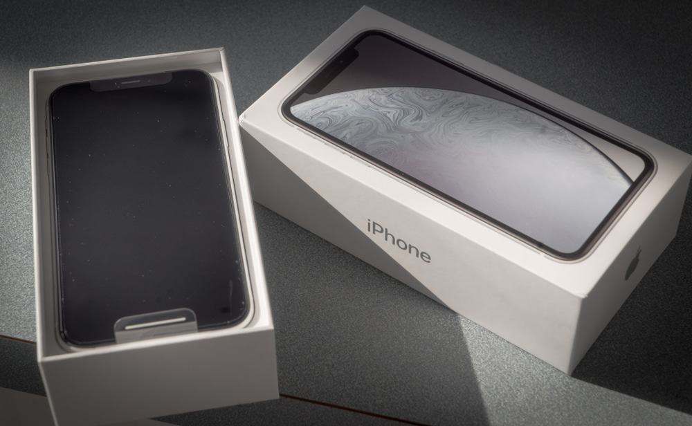 Imagem mostra iPhone, da Apple, dentro da caixa do dispositivo que está aberta. A tampa da caixa aparece ao lado.