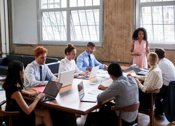 Equipe liderada por uma mulher, em volta de uma mesa de reunião
