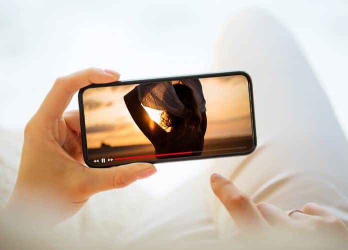 mão segurando um celular reproduzindo um filme