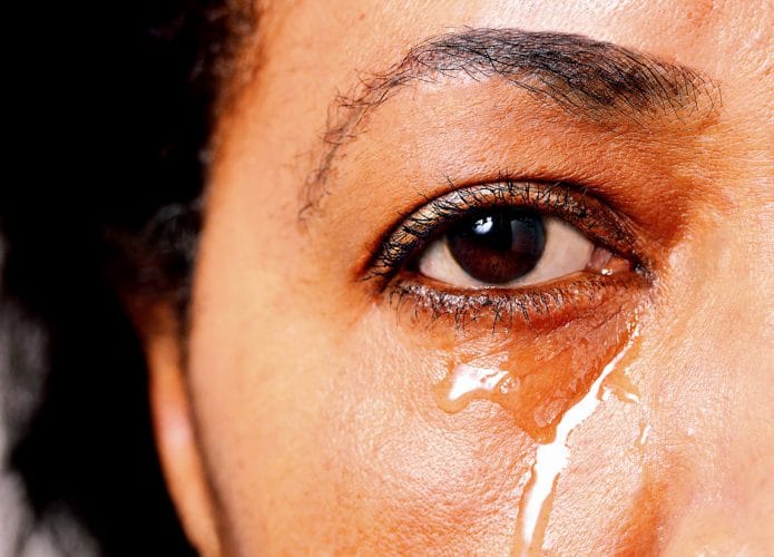 Lágrimas rolam no rosto de uma mulher de pele negra