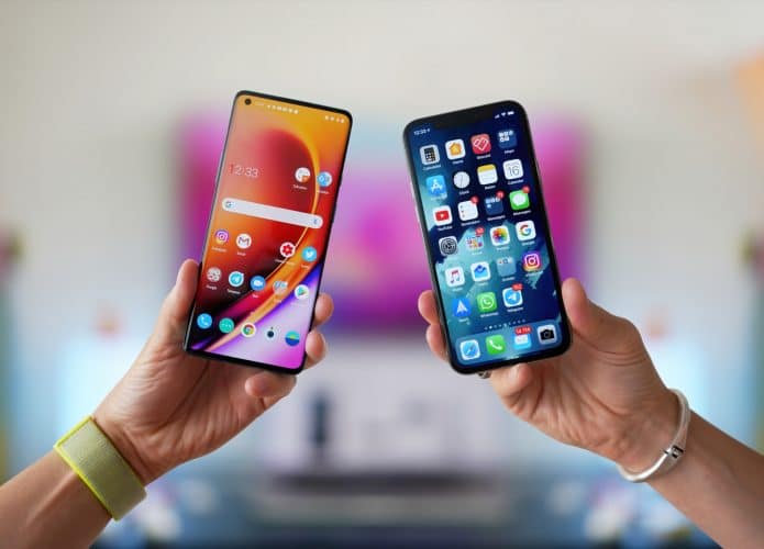 Mãos segurando dois smartphones lado a lado, um iPhone e um Android