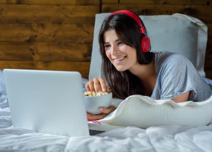 mulher deitada assistindo a filme no notebook