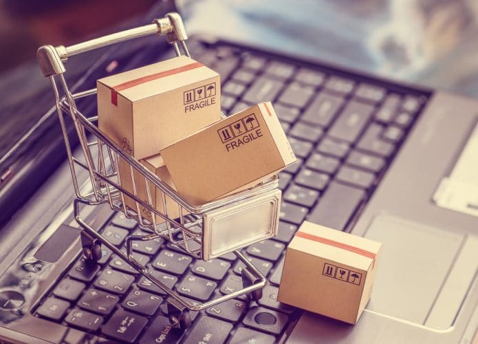 Carrinho de compras em miniatura em cima de um notebook em referência ao Dia do Consumidor