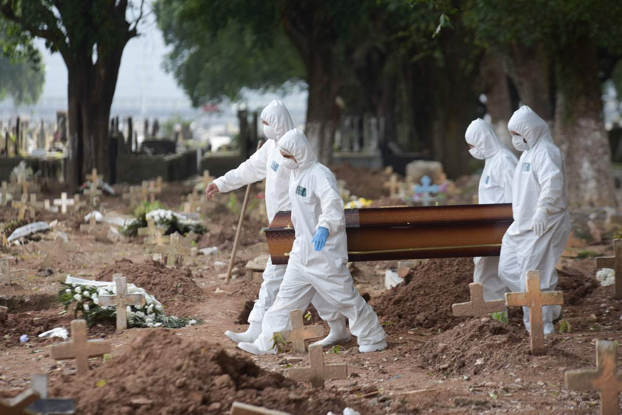 Coveiros carregando um caixão de uma vítima morta pela Covid-19