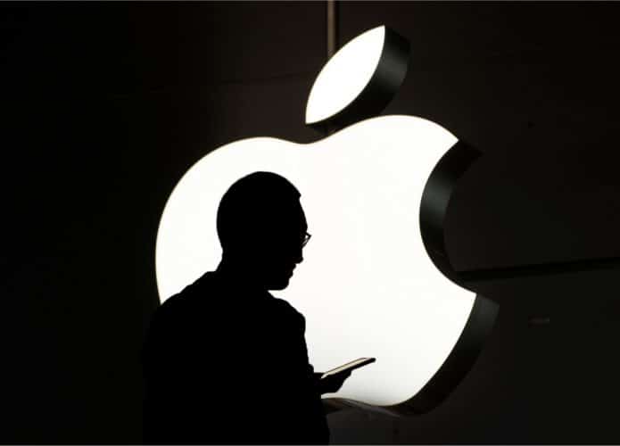 Imagem mostra a logomarca da Apple ao fundo, bem iluminada e acompanhada de uma silhueta de seu fundador, Steve Jobs