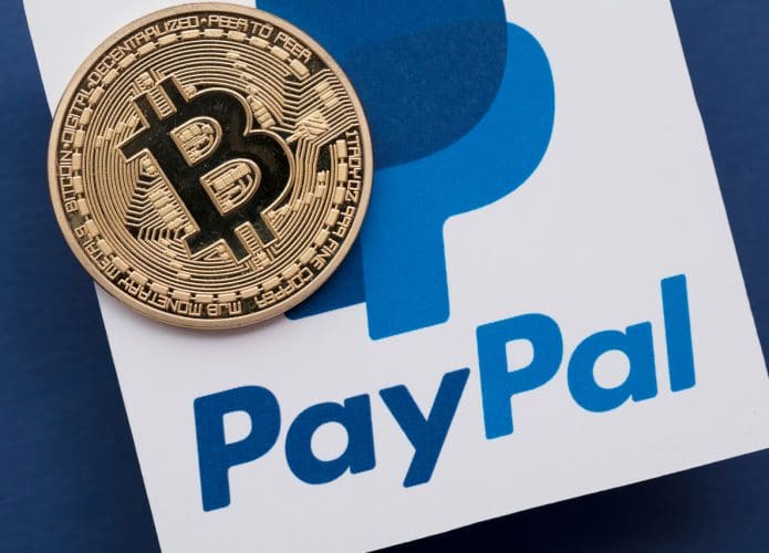 Ilustração de criptomoedas em cima de uma logo do PayPal