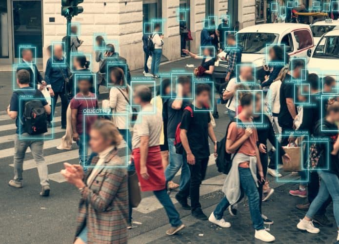 Rua cheia de pedestres, com um quadradinho verde em cima de cada rosto, indicando que há uma tecnologia de reconhecimento facial atuando no cenário