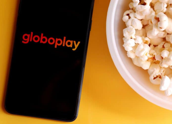 Celular com a logo do Globoplay ao lado de um balde de pipoca