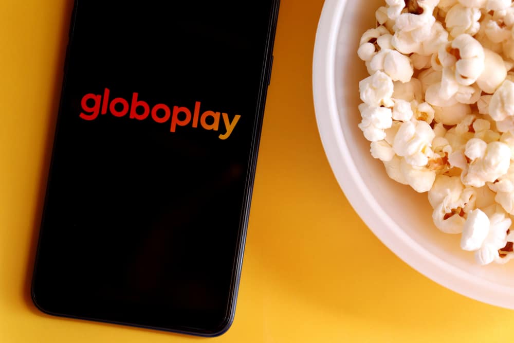 Celular com a logo do Globoplay ao lado de um balde de pipoca