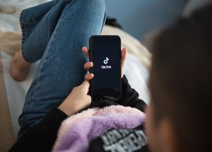 menina segura o celular no appTikTok. Imagem: Shutterstock