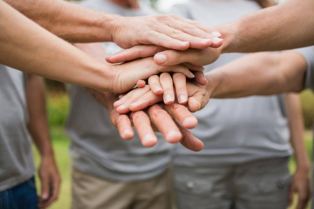 Voluntários unidos com as mãos dadas