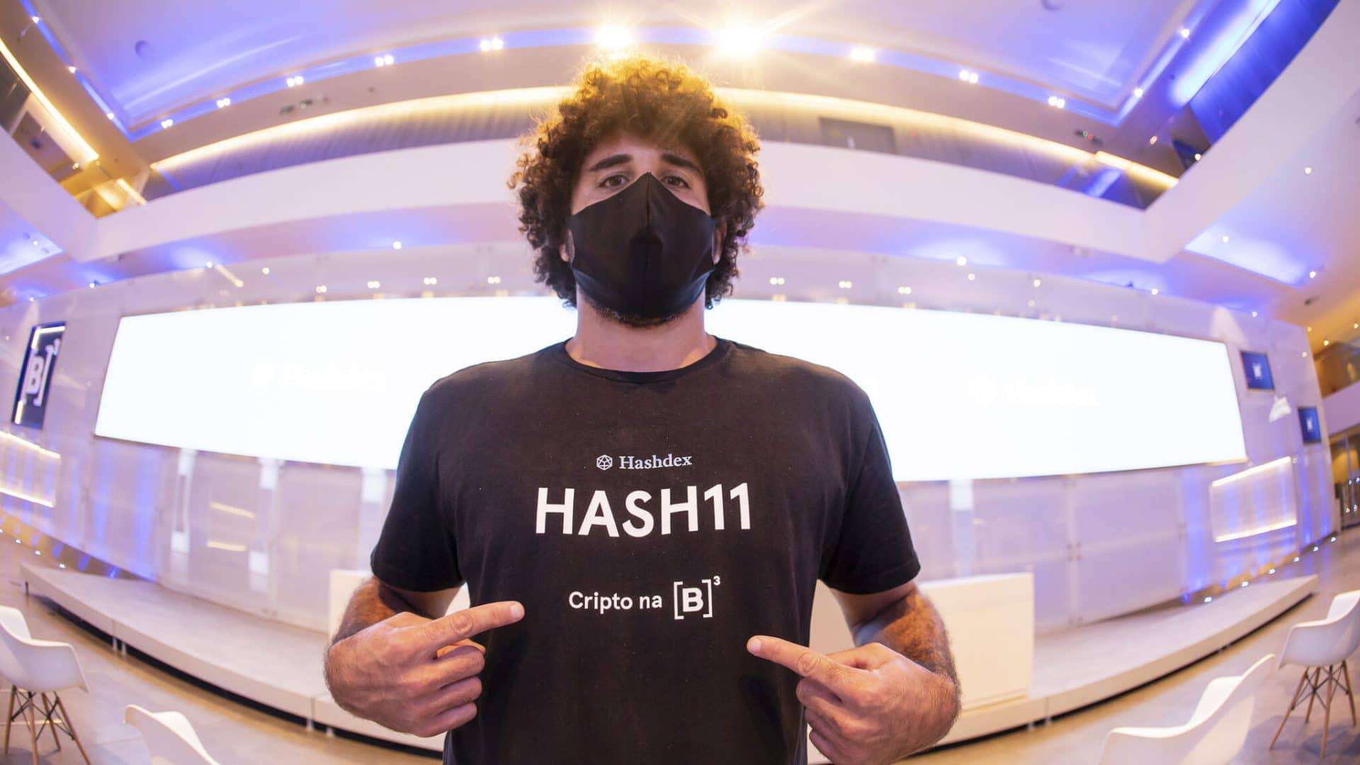 Imagem mostra um jovem com uma camiseta onde pode-se ler a palavra HASH11, sigla do ticker de negociação do primeiro fundo ETF de criptomoedas brasileiro