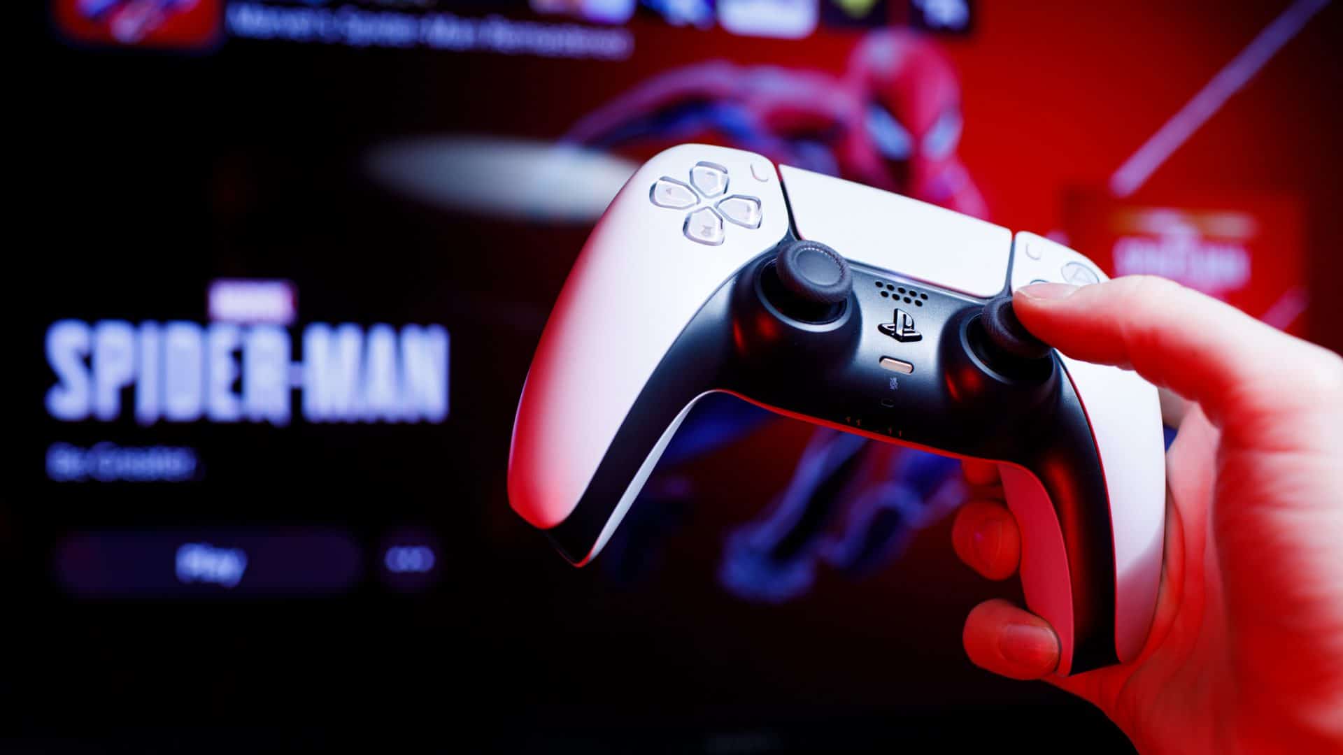Uma mão segura o controle DualSense, do PlayStation 5, com o jogo 