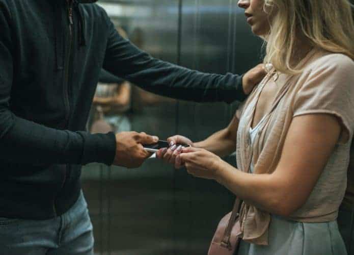 Ladrão roubando smartphone de uma mulher em um elevador