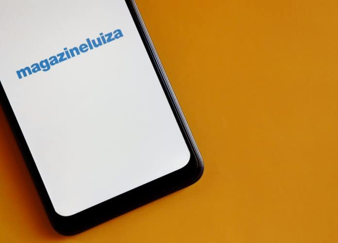 Em uma superfície amarela, um smartphone exibe em sua tela o logo da Magazine Luiza, ou Magalu